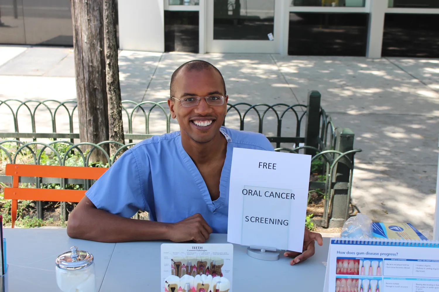 Dr. Shirley at an outdoor table offering free oral cancer screenings