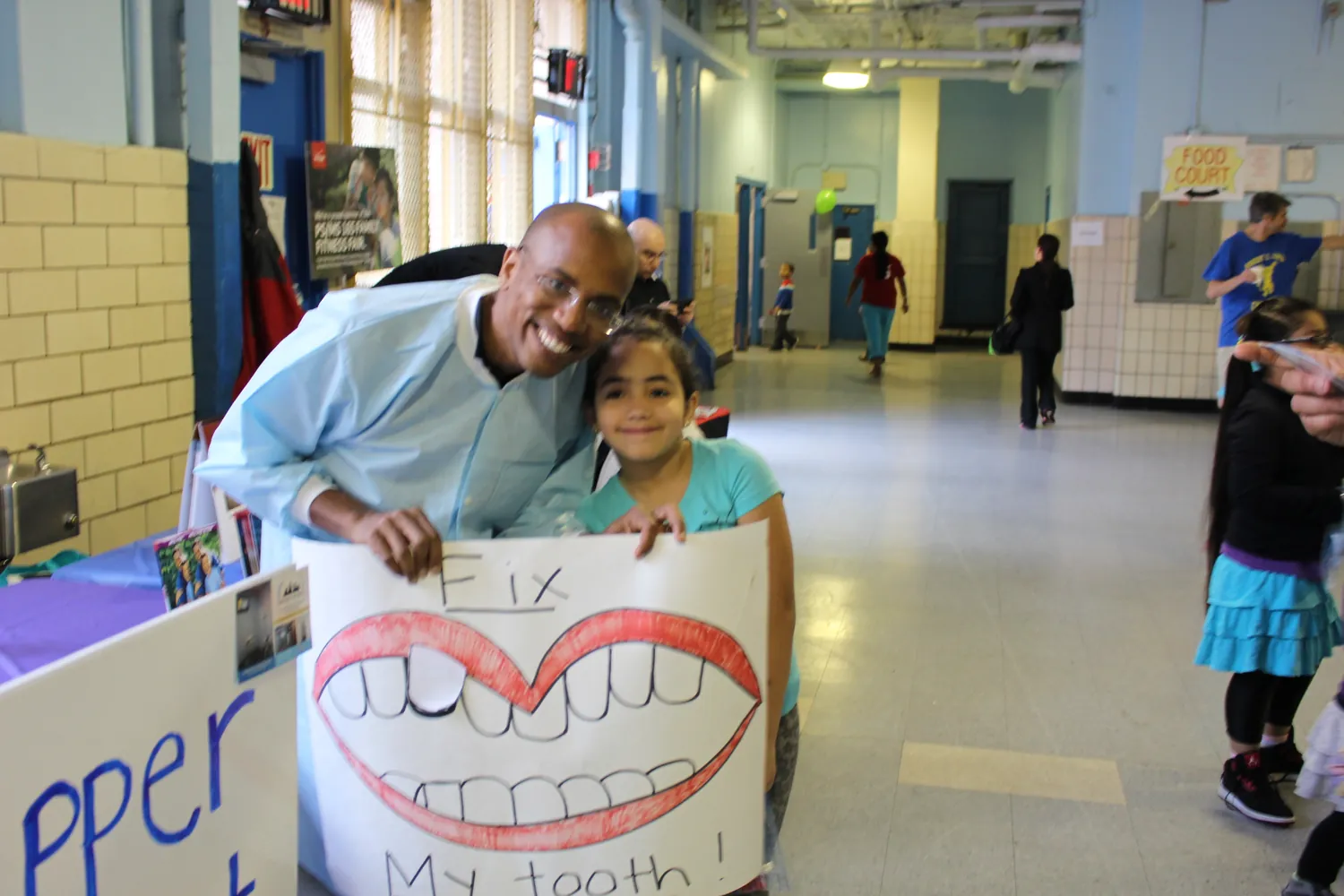 Dr. Shirley with a student holding a hand-drawn smile poster at a school